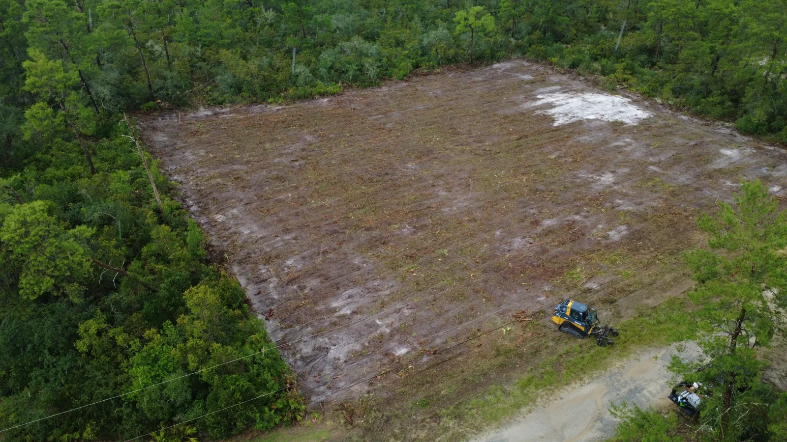 Track loader clearing and grading a wooded acre in Crescent City Putnam County FL