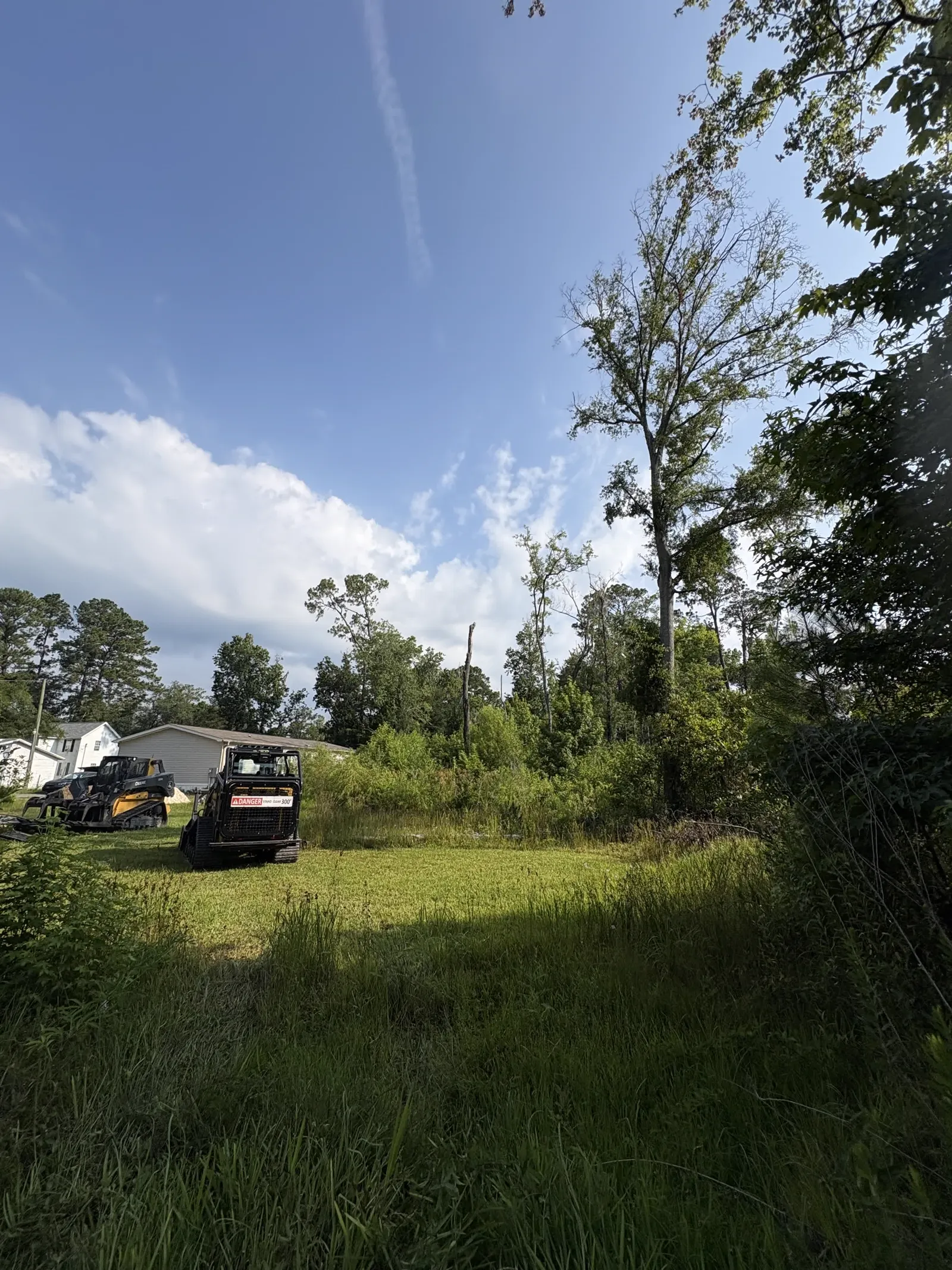 Skid steer forestry mulcher clearing an overgrown lot in Lake City Columbia County FL